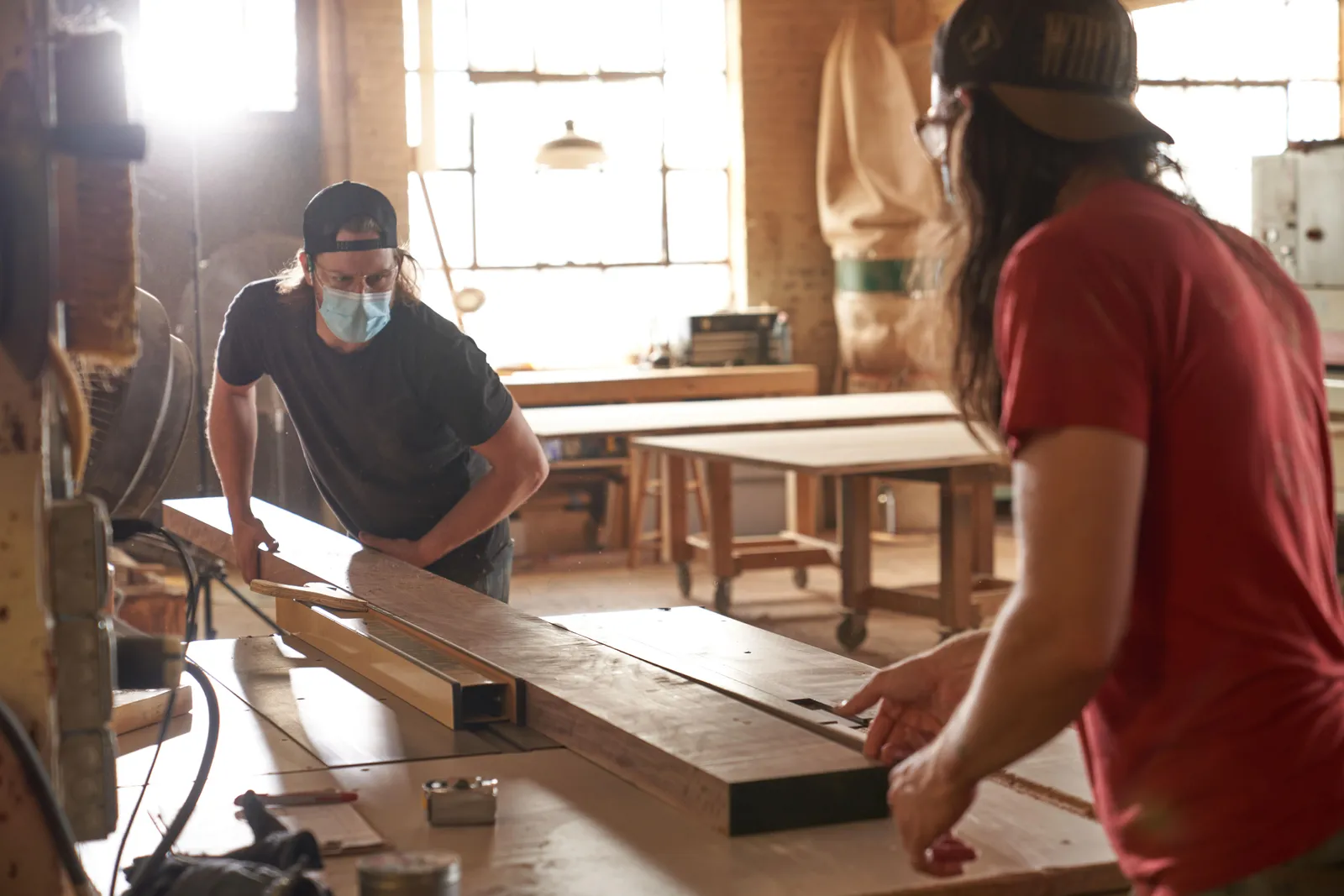 Two men sawing wood in a wood shop