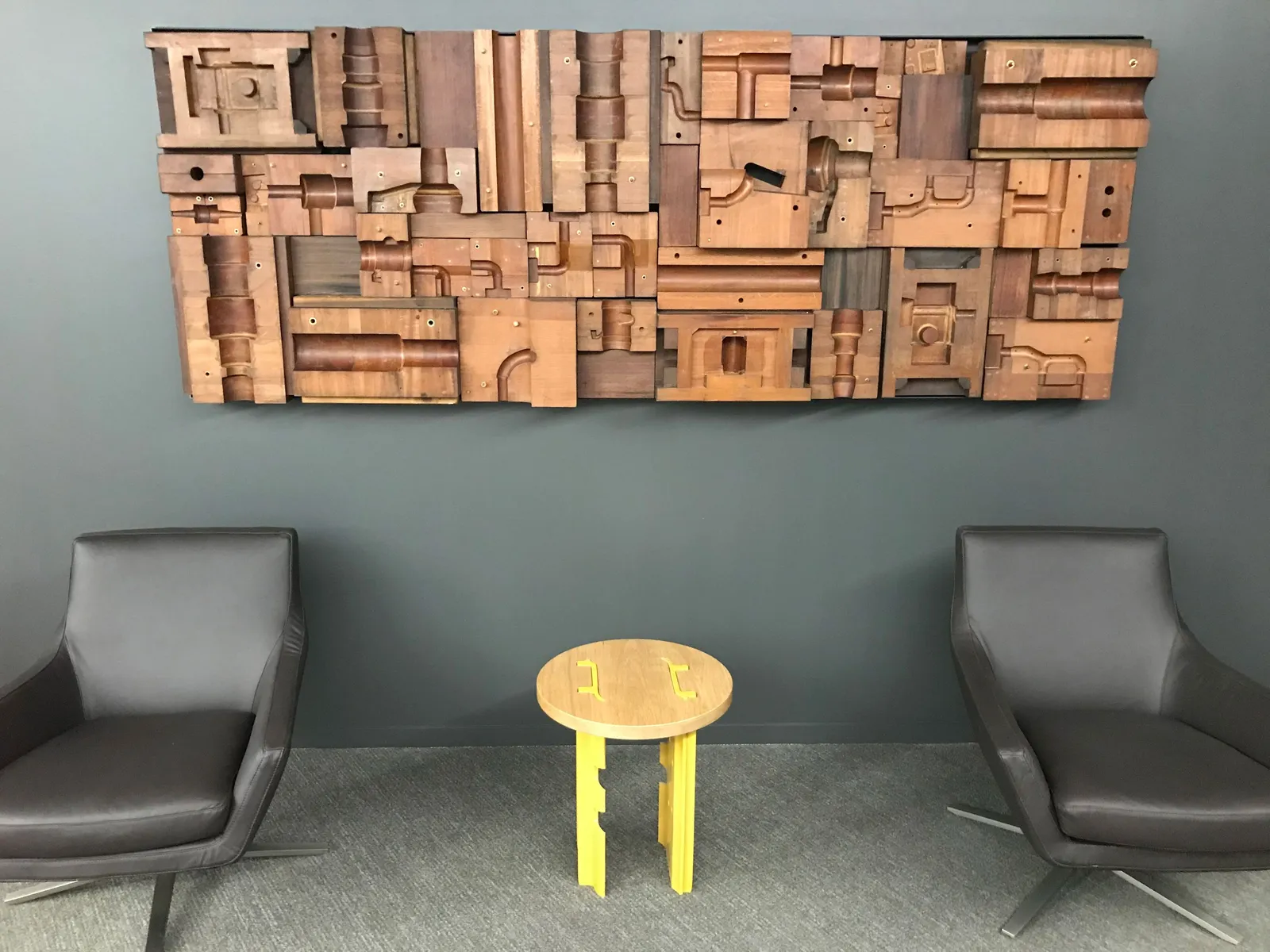 custom feature wall made from company's historical machinery parts by Icon Modern