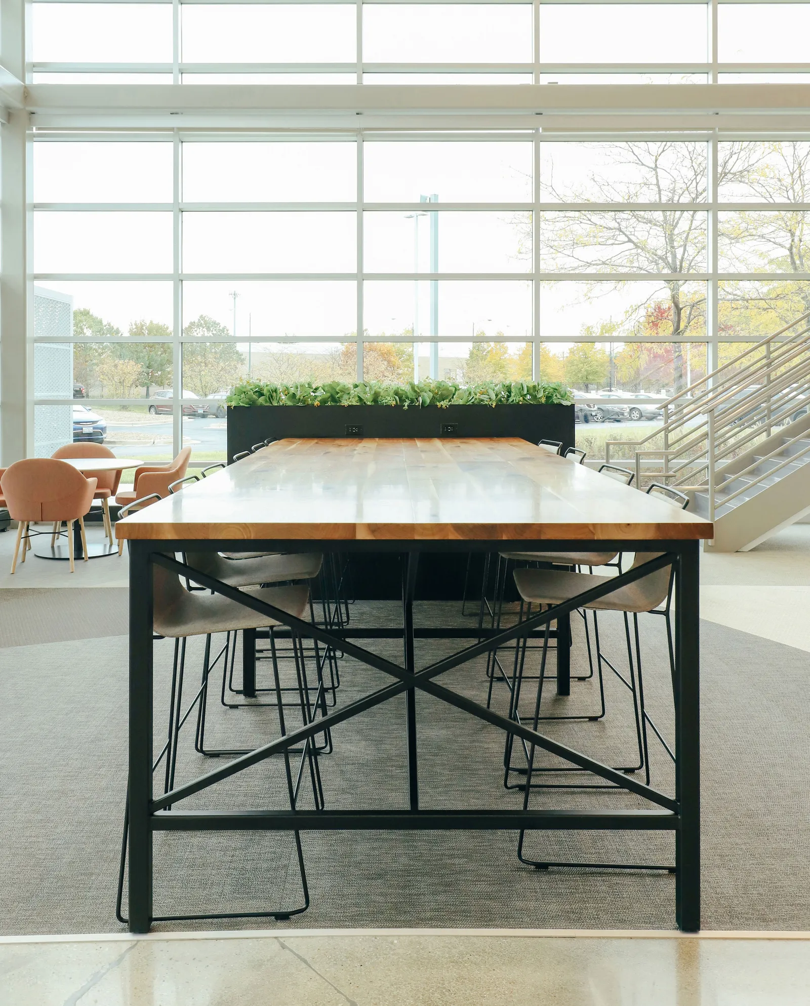 custom community table in walnut with steel tube base and foot rest by Icon Modern
