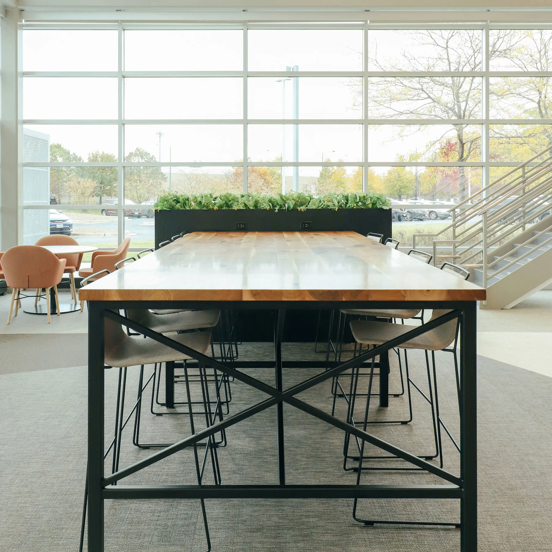 custom community table in walnut with steel tube base and foot rest by Icon Modern