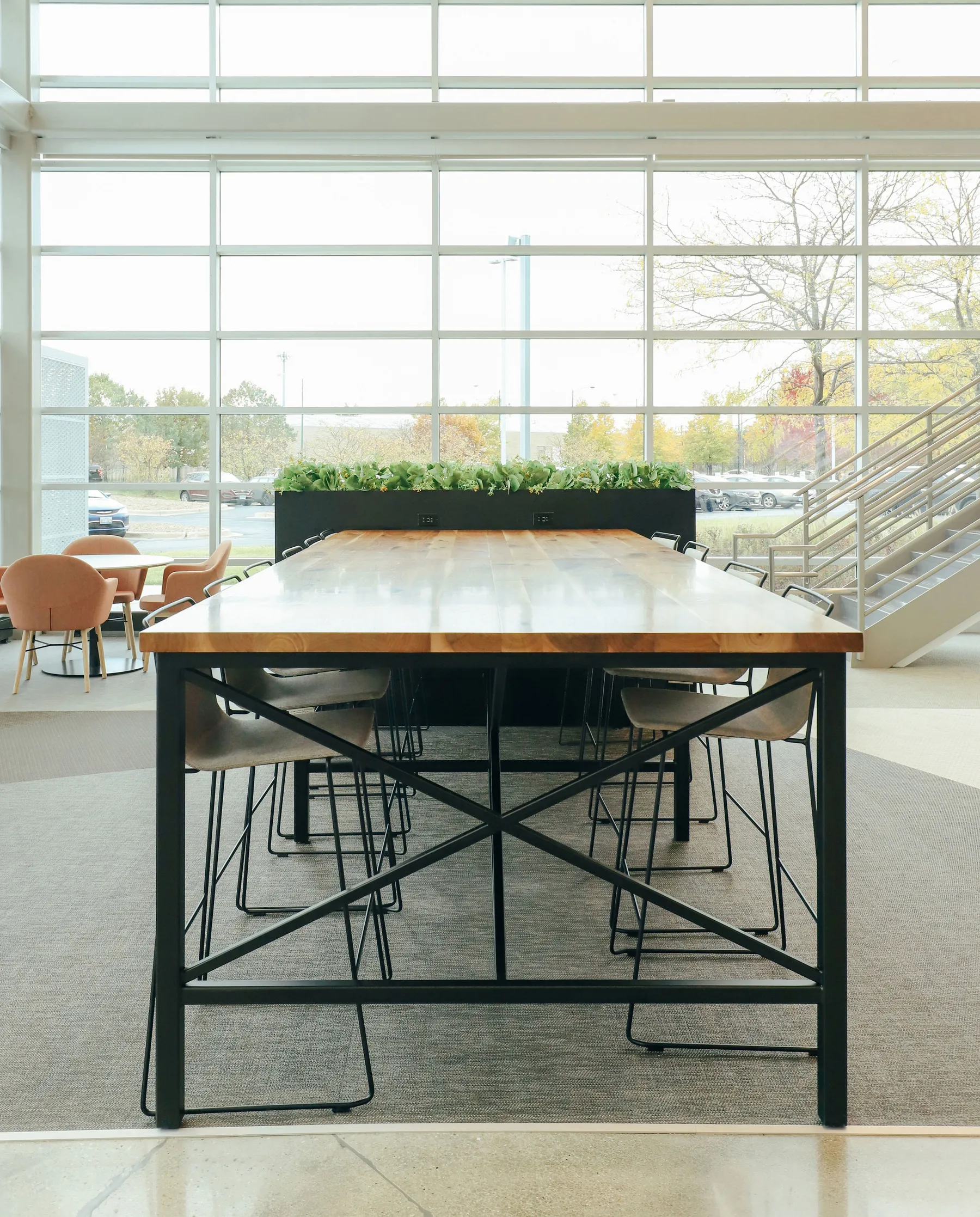custom community table in walnut with steel tube base and foot rest by Icon Modern