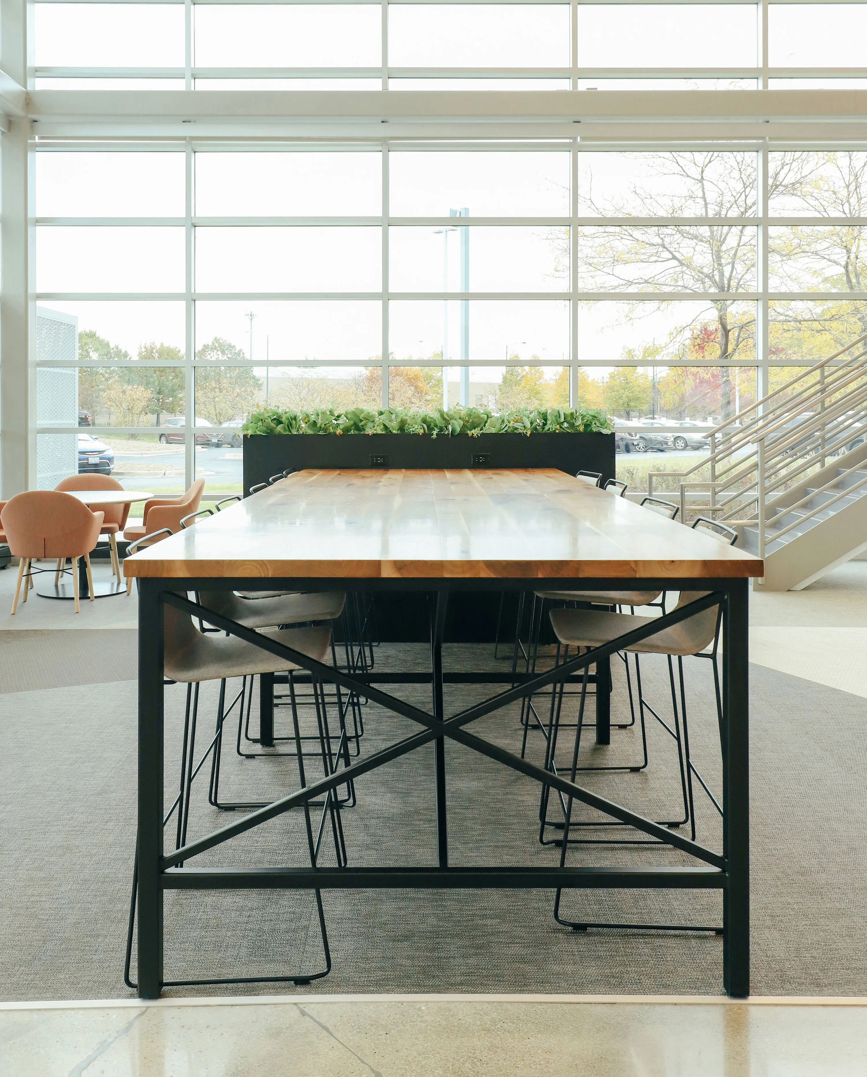custom community table in walnut with steel tube base and foot rest by Icon Modern
